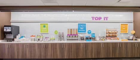 A self-service breakfast area with various food and drink options, including yogurt, waffle boats, and eggs.