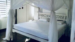 Ein Bett mit Baldachin, ein Nachttisch und ein Fenster mit Jalousien.
