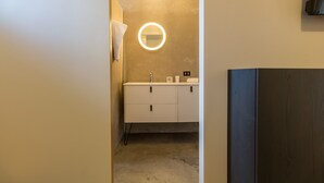 Een moderne badkamer met een wastafel, een ronde spiegel en een handdoek aan de muur.