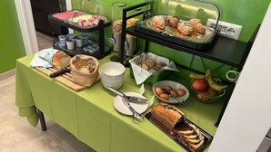 A buffet setup with various food items, including bread, pastries, and fruits.