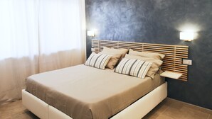 A bedroom with a bed, a nightstand, and a wall-mounted light.