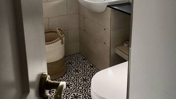 Un baño con un lavabo blanco, un inodoro y una ventana con plantas en macetas.