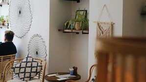 A cozy cafe interior with wicker chairs, a round wooden table, and decorative wall hangings. - Upstairs at 33 (Worcester)