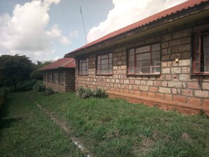 A two-story stone building with a red roof and multiple windows. - Mwingi Cottage Hotel (Mwingi)