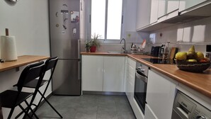 A modern kitchen with white cabinets, a stainless steel refrigerator, a Bosch washing machine, and a window providing natural light. - BEAUTIFUL APARTMENT ON THE SEA OF THE SEA. (moya)