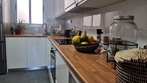 A modern kitchen with white cabinets, a wooden countertop, a washing machine, and a window with blinds. - BEAUTIFUL APARTMENT ON THE SEA OF THE SEA. (moya)