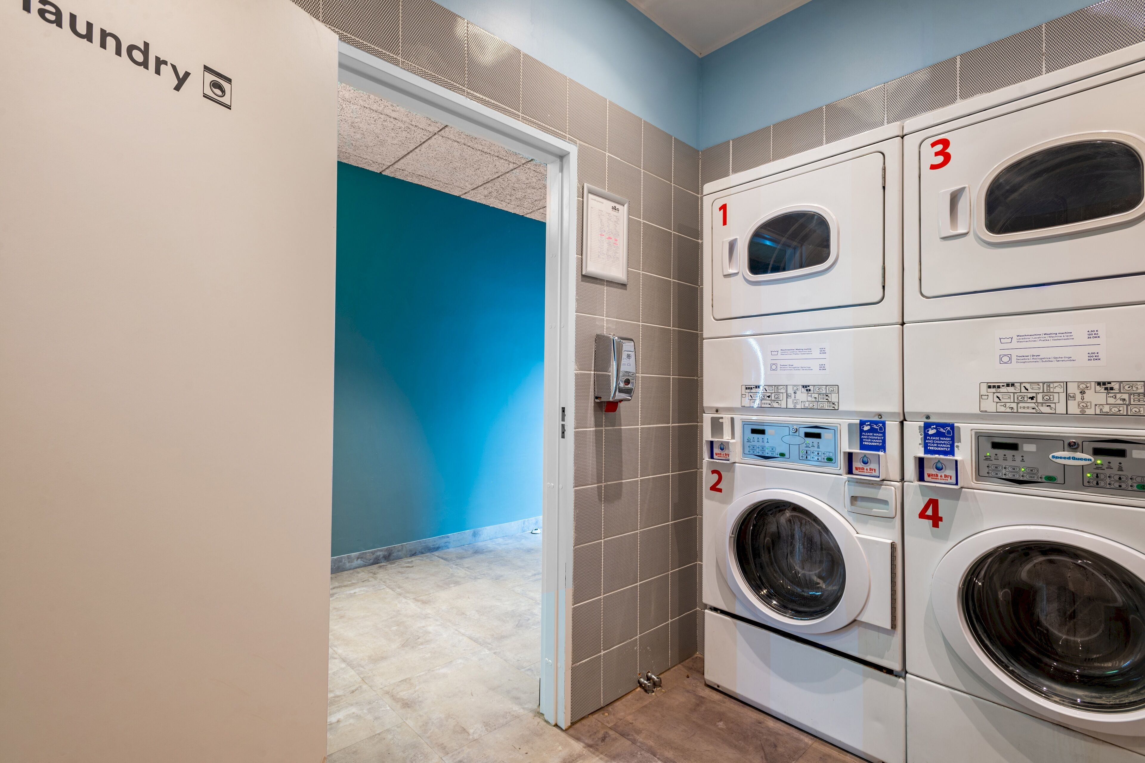 A laundry area with four washing machines, numbered 1 to 4, and a blue wall in the background.