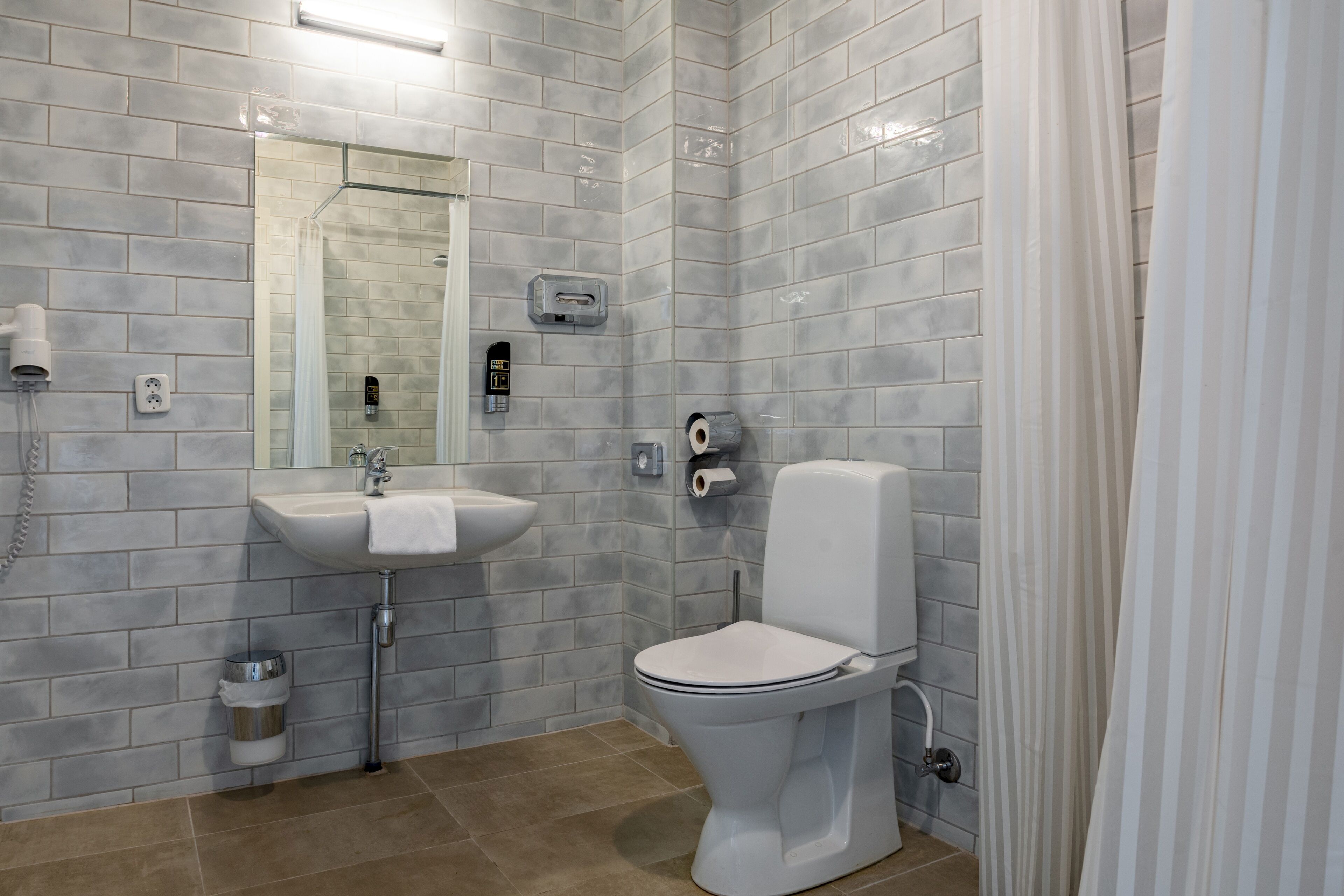 A modern bathroom with a white sink, toilet, and shower.