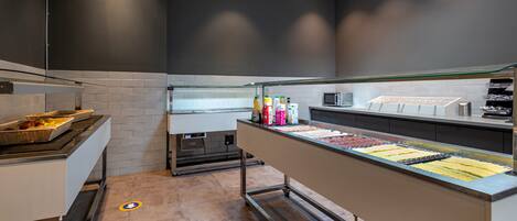 Uma cozinha moderna com serviço de buffet, incluindo uma cesta de frutas e diversos condimentos.