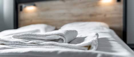 Una cama bien hecha con sábanas blancas y cabecera de madera.