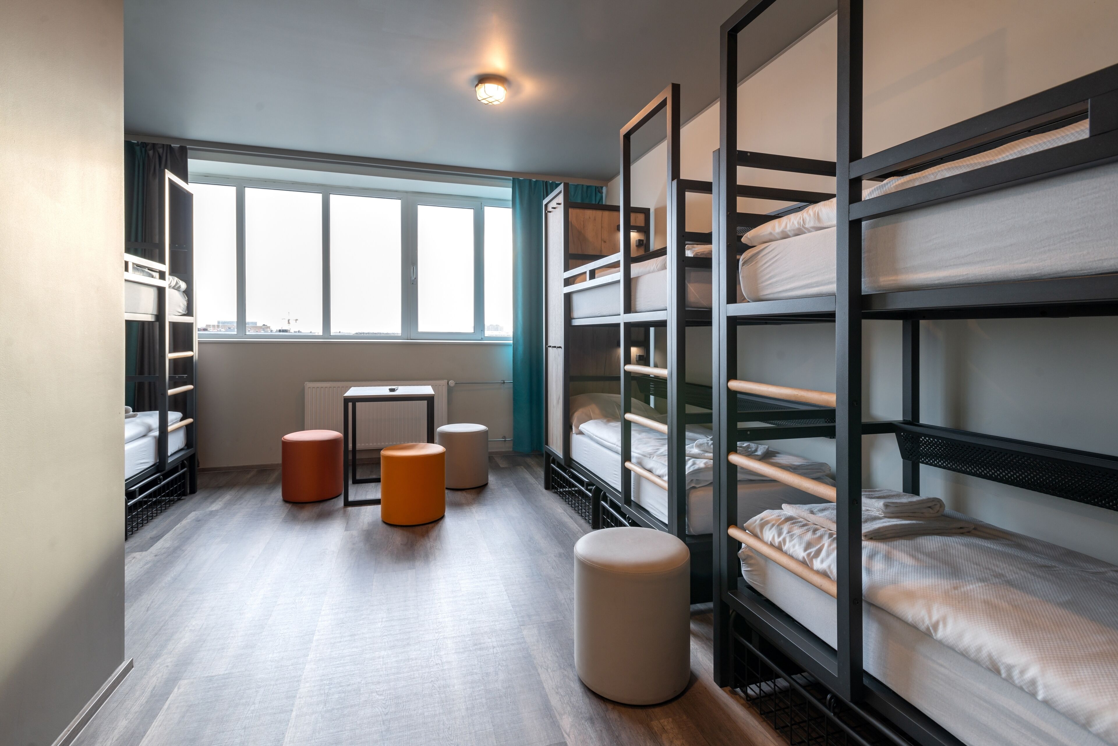 Een slaapzaal met stapelbedden, een raam en een radiator.