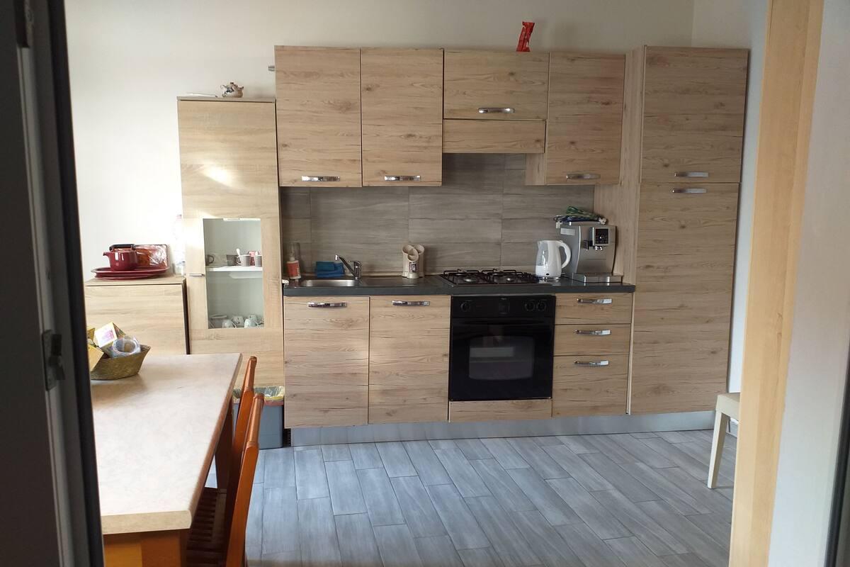 A modern kitchen with wooden cabinets, a black oven, and a stainless steel sink.