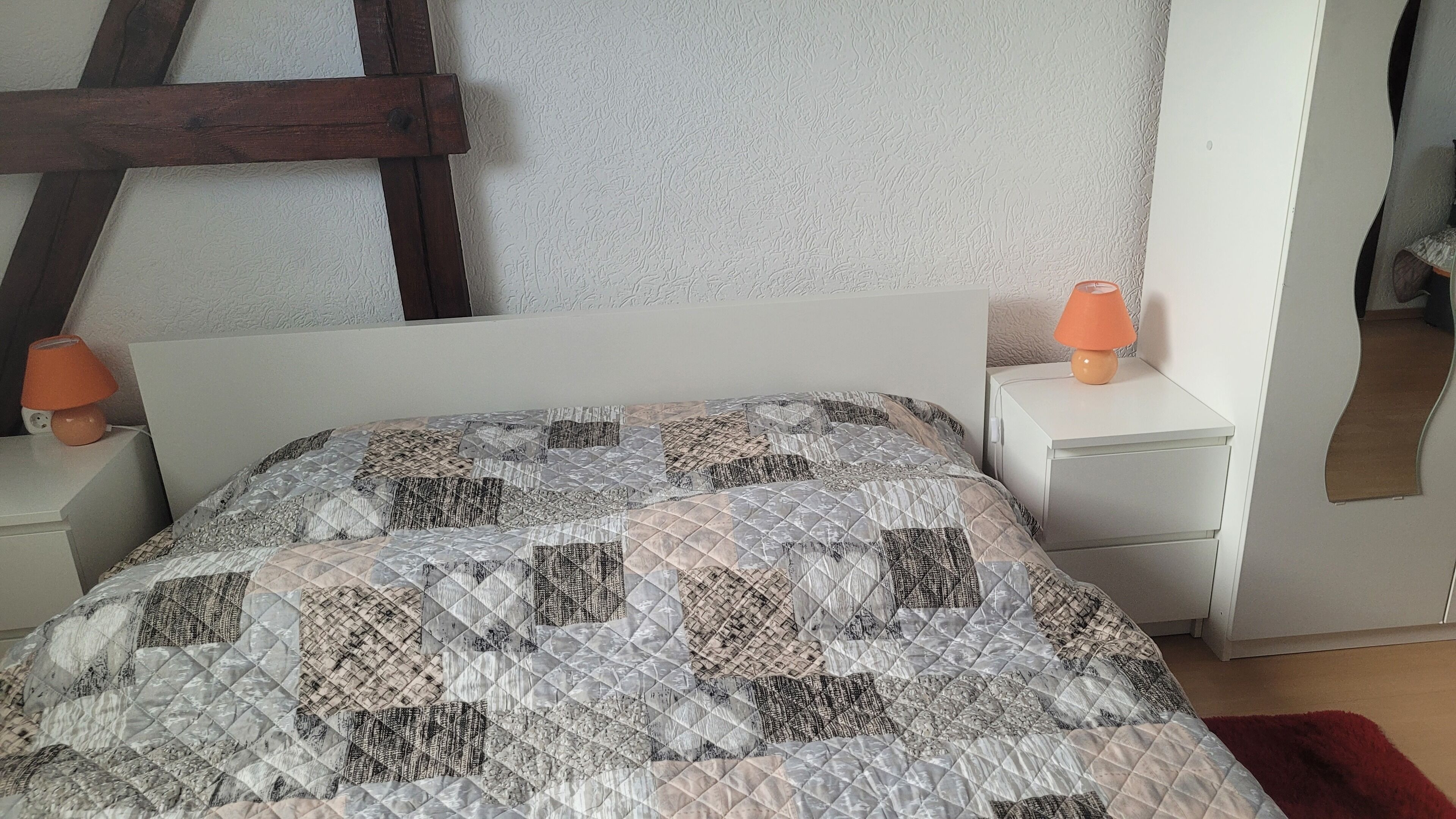 Une chambre à coucher avec un lit, une table de chevet, une lampe et un miroir.