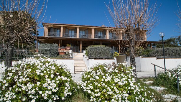 A two-story building with a balcony, surrounded by flowering bushes and a clear blue sky. - GFH - Hotel Palazzo Bello (Recanati)