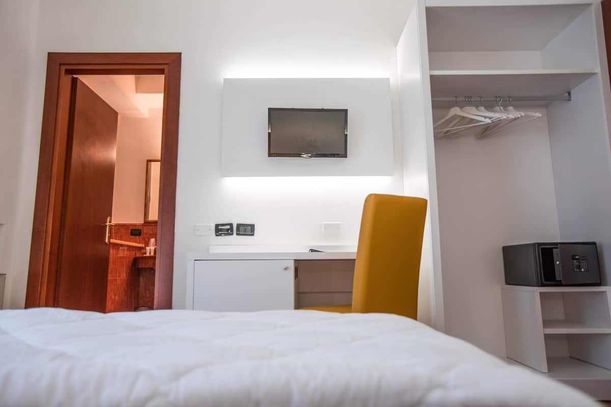 Une chambre d’hôtel comprenant un lit, un bureau avec une chaise, une armoire et un téléviseur fixé au mur.
