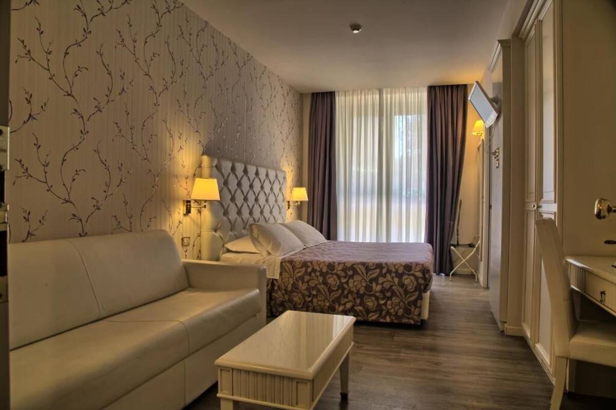 Une chambre d’hôtel comprenant un lit, un canapé, une table basse et un bureau avec une lampe.