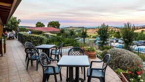 An outdoor patio with tables and chairs, overlooking a pool and a hilly landscape. - GFH - Hotel Palazzo Bello (Recanati)