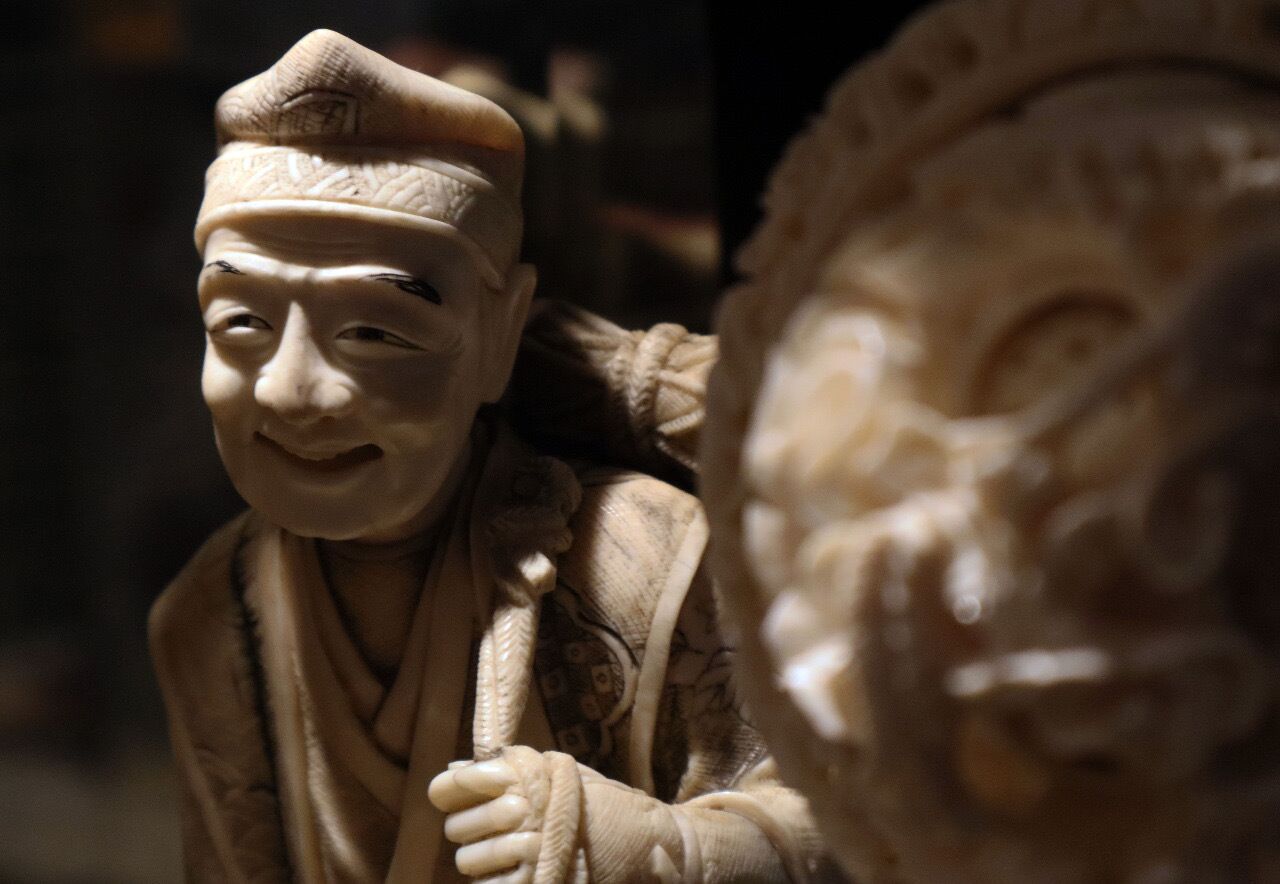 A close-up of a sculpture with intricate carvings and a figure wearing a traditional robe.