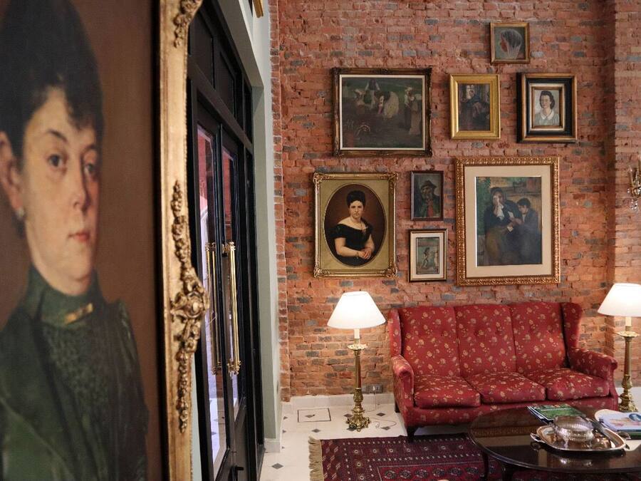 Une pièce avec un canapé rouge, deux lampes et un mur en briques orné de tableaux encadrés.