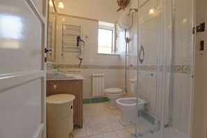 Enjoy a refreshing shower in the modern bathroom with a glass-enclosed shower area, sink, toilet, and bidet.