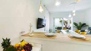 Cozinha moderna com uma fruteira, uma televisão de tela plana e luminárias pendentes.