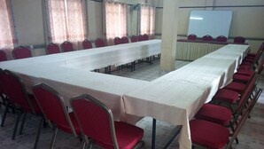 A conference room with a long table, red chairs, and a whiteboard. - Pinnacle Guest House (Mwingi)