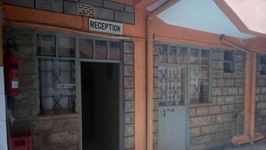 A reception area with a sign, a door labeled "P102", and a fire extinguisher. - Pinnacle Guest House (Mwingi)
