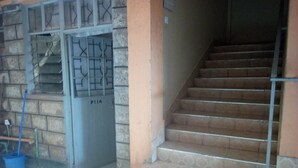 A staircase with a metal railing leading to a door marked P114. - Pinnacle Guest House (Mwingi)