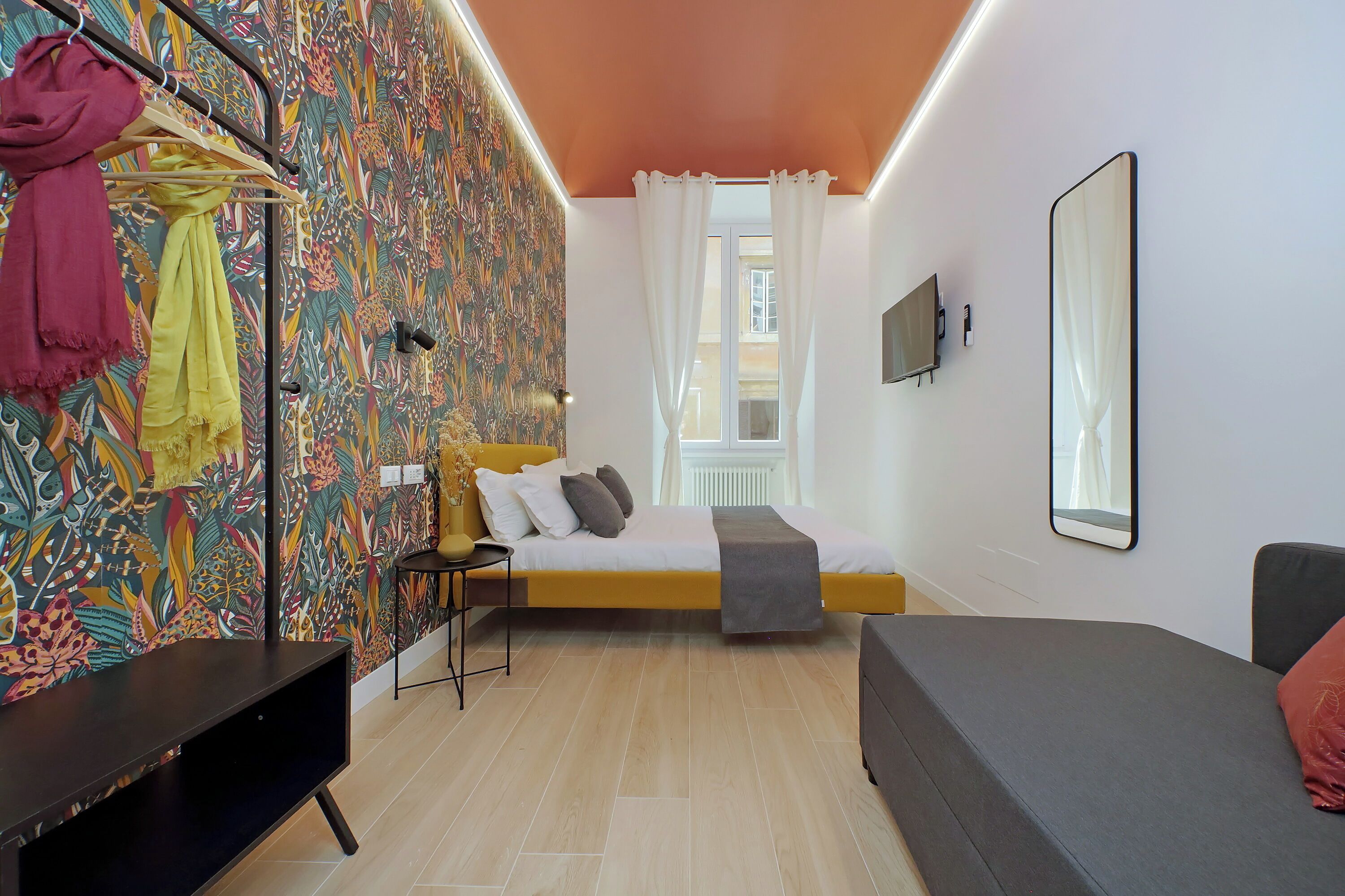 Une chambre à coucher moderne avec un lit, un canapé, une télévision et une armoire.