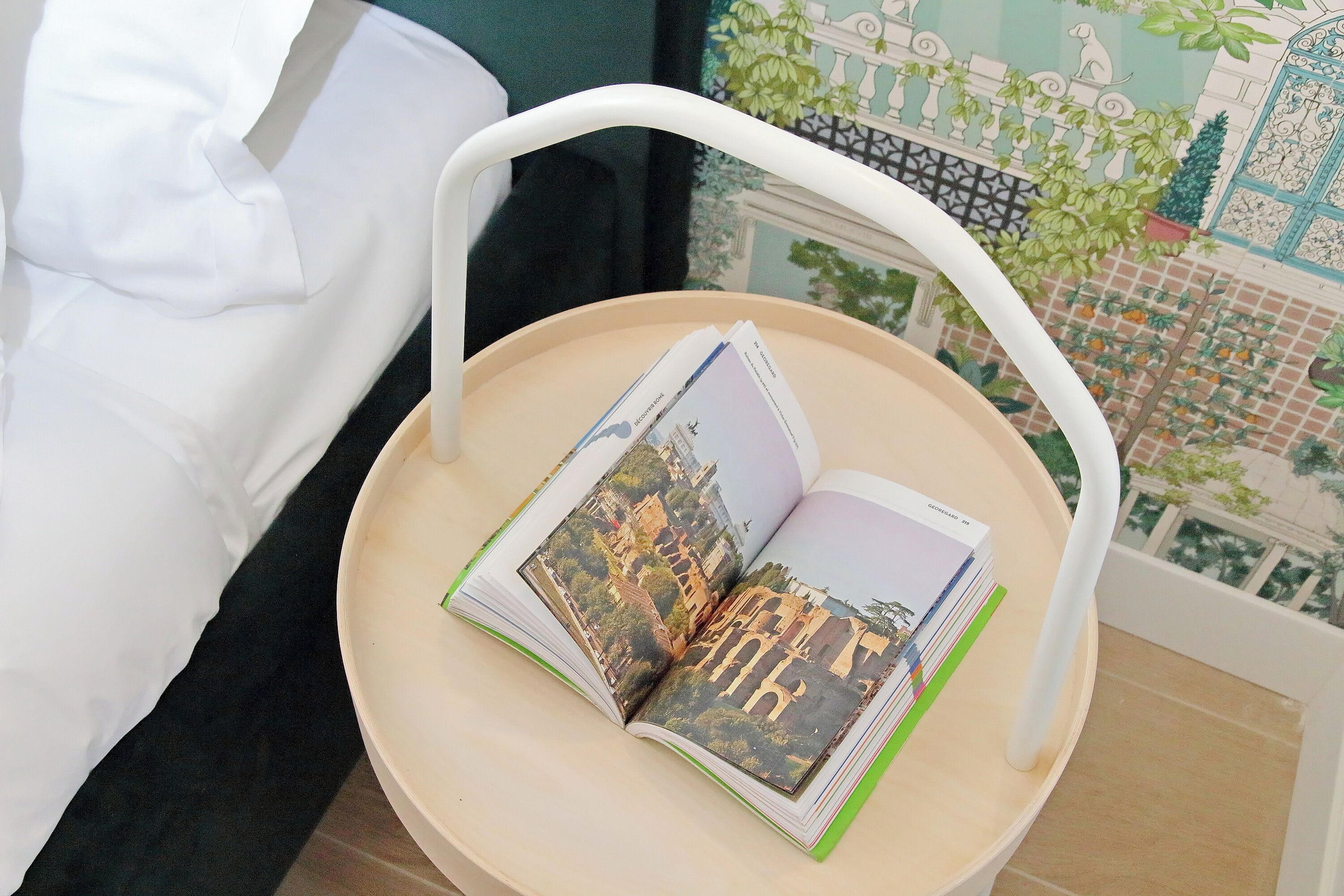 Un livre posé sur une table ronde, à côté d’une chaise blanche.