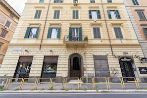 Un edificio de varios pisos con una entrada central, balcones y un letrero que dice 'Arch Romani Restaurant'.