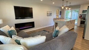 A modern living room with a fireplace, a flat-screen TV, and a grey sofa with decorative pillows.