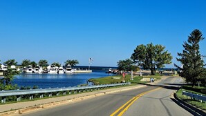 A coastal road with a marina on the left, featuring several boats docked.