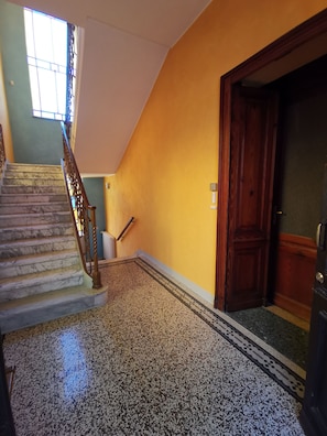 A staircase with marble steps leading to a landing with a patterned floor.