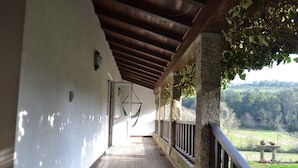 A stone staircase leading to a covered porch with a wooden ceiling and a view of a green landscape. - Casas de Pindela (Vila Nova de Famalicao)