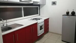 A kitchen with a gas stove, a microwave, and a refrigerator. - House in private subdivision (Aguascalientes)