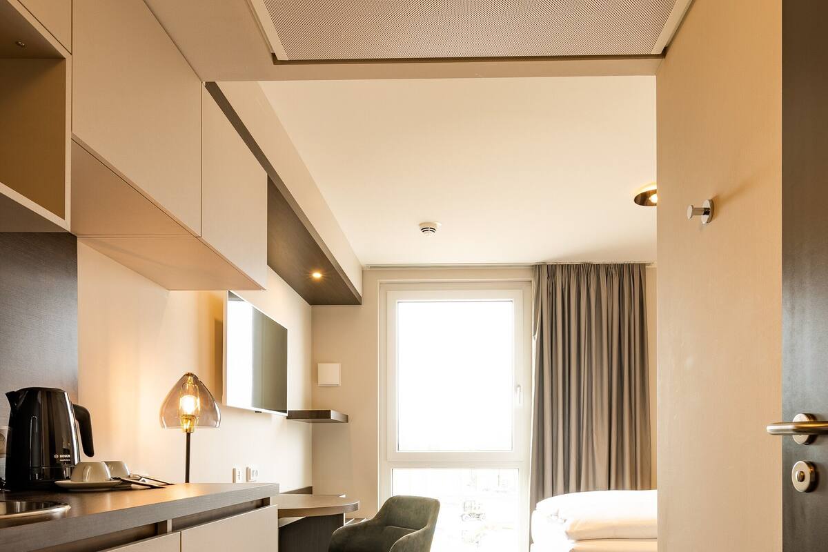 Une chambre d’hôtel moderne équipée d’une kitchenette, d’un coin repas et d’un lit.