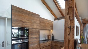 A modern kitchen with wooden cabinetry, a built-in oven, and a coffee machine.