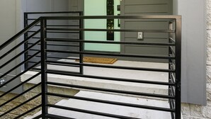 A staircase with black railings leading to a door with a green door frame.