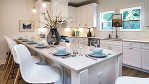A modern kitchen with white cabinets, a marble island, and pendant lighting.