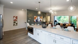A modern kitchen with white cabinets, a large island, and pendant lighting.