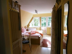 Un dormitorio con cama, una silla, un ventanal y un radiador.