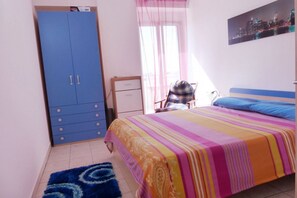 A bedroom with a bed, a wardrobe, a chair, and a window with curtains.