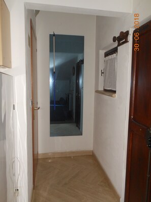 A hallway with a mirror and a door leading to a room.