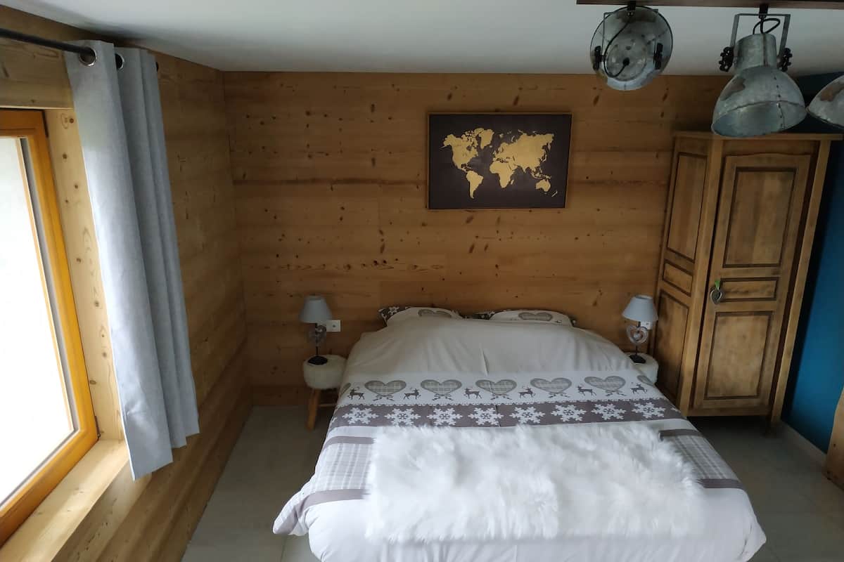 A wooden-paneled room with a bed, a world map on the wall, and a wardrobe.