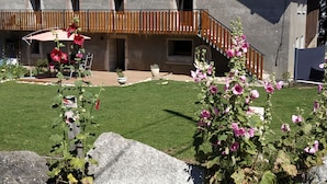A house with a balcony, a lawn, and a garden with flowers. - Chambre d'Hotes des Bassins (Saint-Paul-en-Chablais)