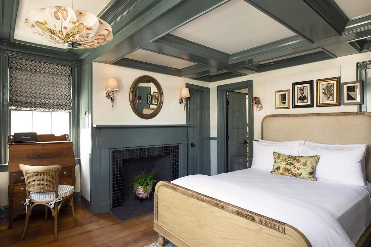 Une chambre à coucher comprenant un lit, une commode, une chaise, une cheminée et des lampes fixées au mur.