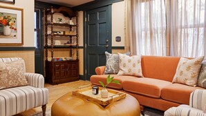 A cozy living room with striped sofas, a wooden coffee table with a vase and candle, and a bookshelf with decorative items. - Life House, Nantucket (Nantucket)