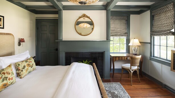 A bedroom with a bed, a fireplace, a mirror, and a window with a view. - Life House, Nantucket (Nantucket)
