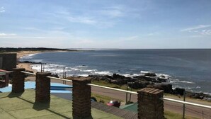 A view of a beach with a clear sky, a pool area with brick pillars, and a road leading to the beach. - Beautiful House Privileged Location Unique View (maldonado)